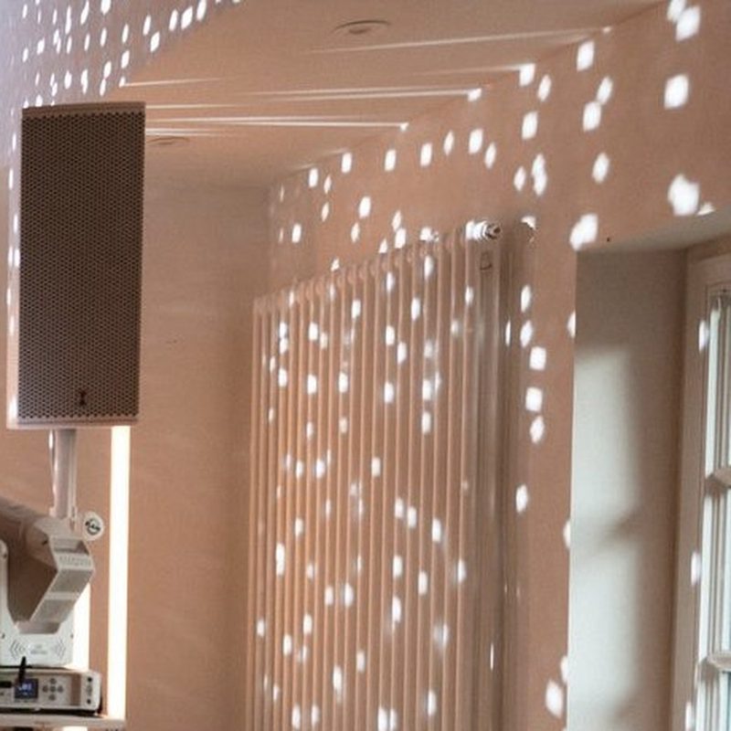 Warm light dots on a white wall from a mirror ball